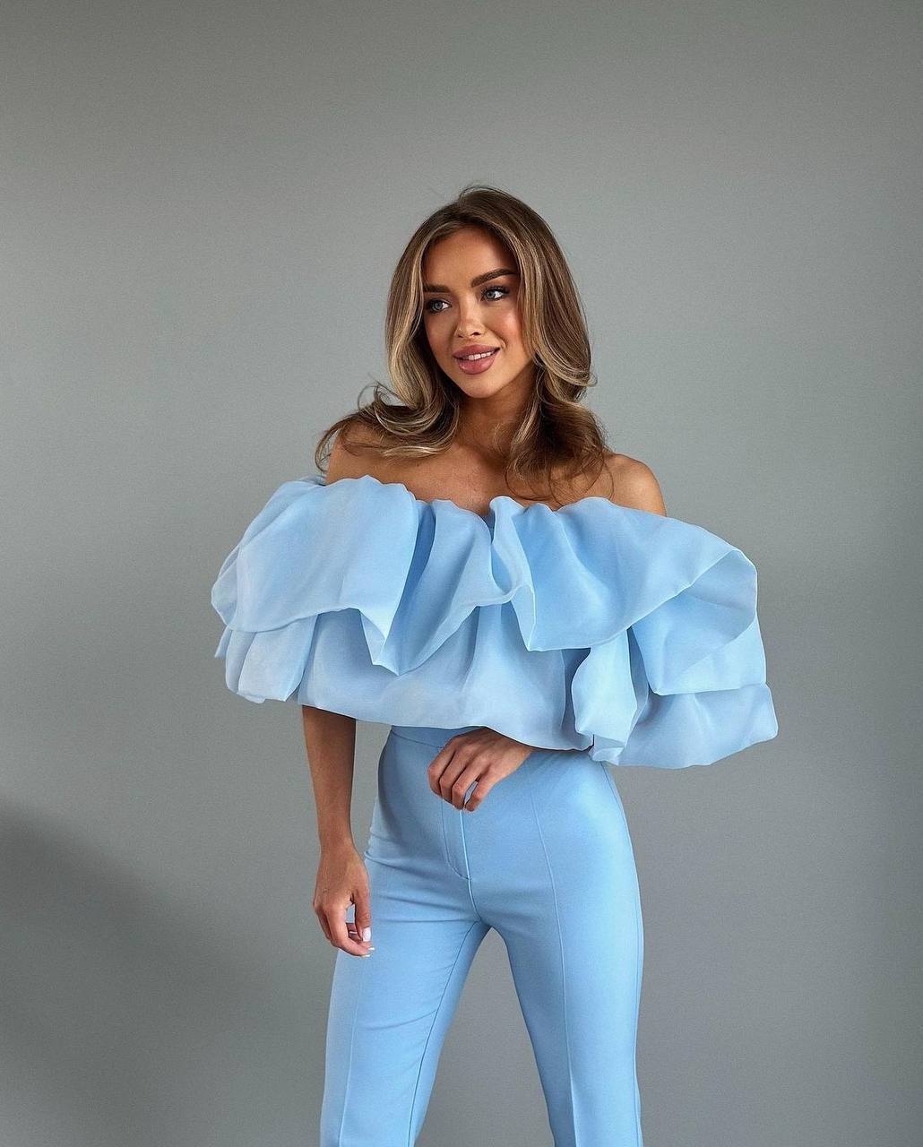 This unique two-piece statement top is designed to create a dramatic, elegant silhouette and instantly elevate any outfit.
The base top is made from a soft, comfortable fabric, while the voluminous ruffles are crafted from lightweight organza, adding movement, airiness, and a couture-inspired look.
The top features elastic bands at the top and bottom, ensuring a secure yet comfortable fit that adapts to the body and stays in place.
The layered construction creates a bold visual effect while remaining light