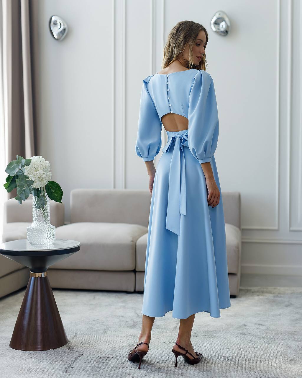 Woman wearing a light blue dress with a backless design in an elegant room.