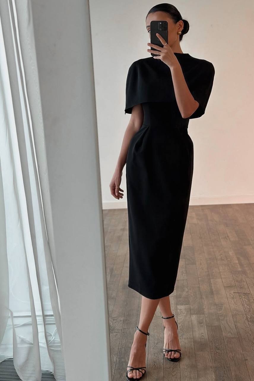 Person wearing a black dress standing in front of a mirror.