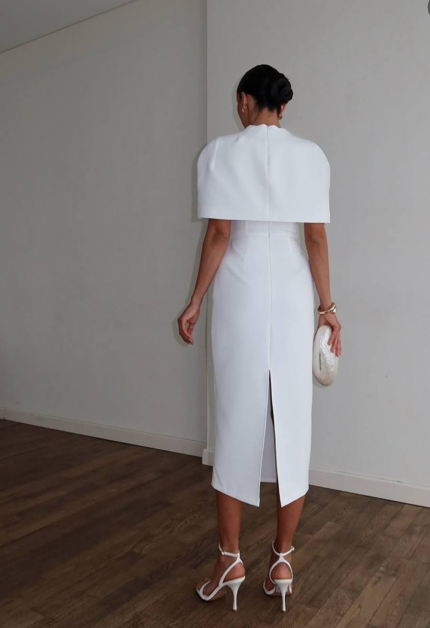 Woman wearing a white outfit with a cape in a minimalistic setting