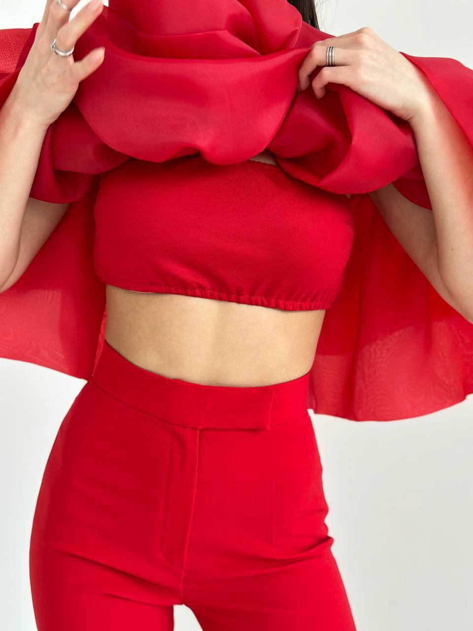 Person wearing a red outfit with a ruffled top on a white background