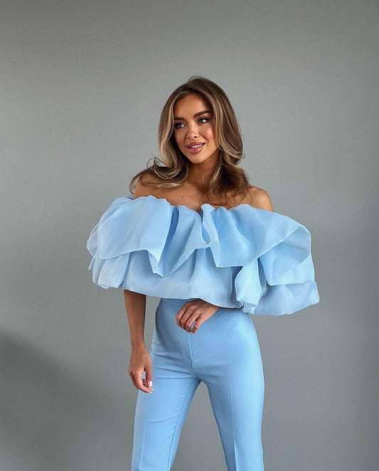 This unique two-piece statement top is designed to create a dramatic, elegant silhouette and instantly elevate any outfit.
The base top is made from a soft, comfortable fabric, while the voluminous ruffles are crafted from lightweight organza, adding movement, airiness, and a couture-inspired look.

The top features elastic bands at the top and bottom, ensuring a secure yet comfortable fit that adapts to the body and stays in place.
The layered construction creates a bold visual effect while remaining light