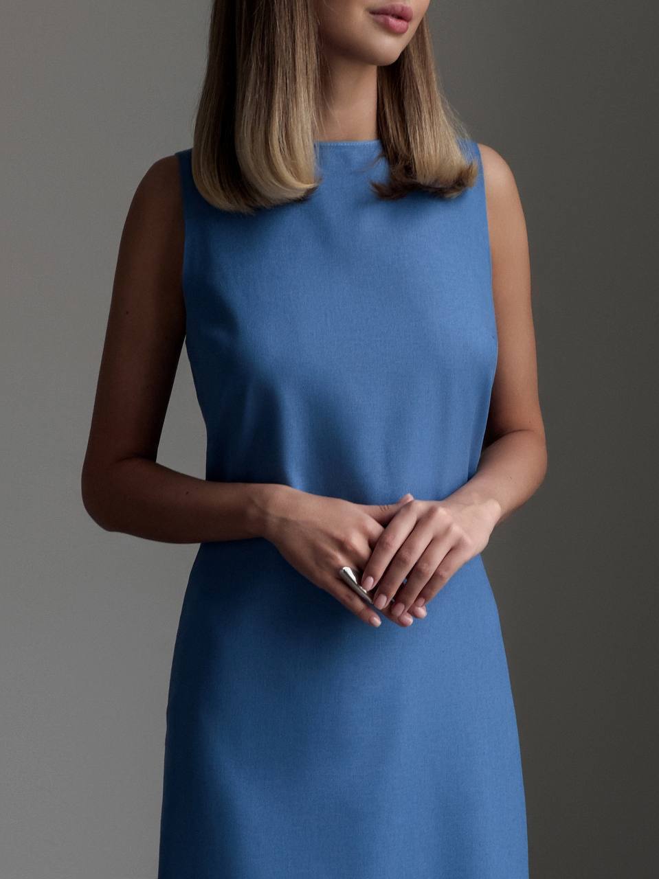 Woman wearing a blue dress against a gray background