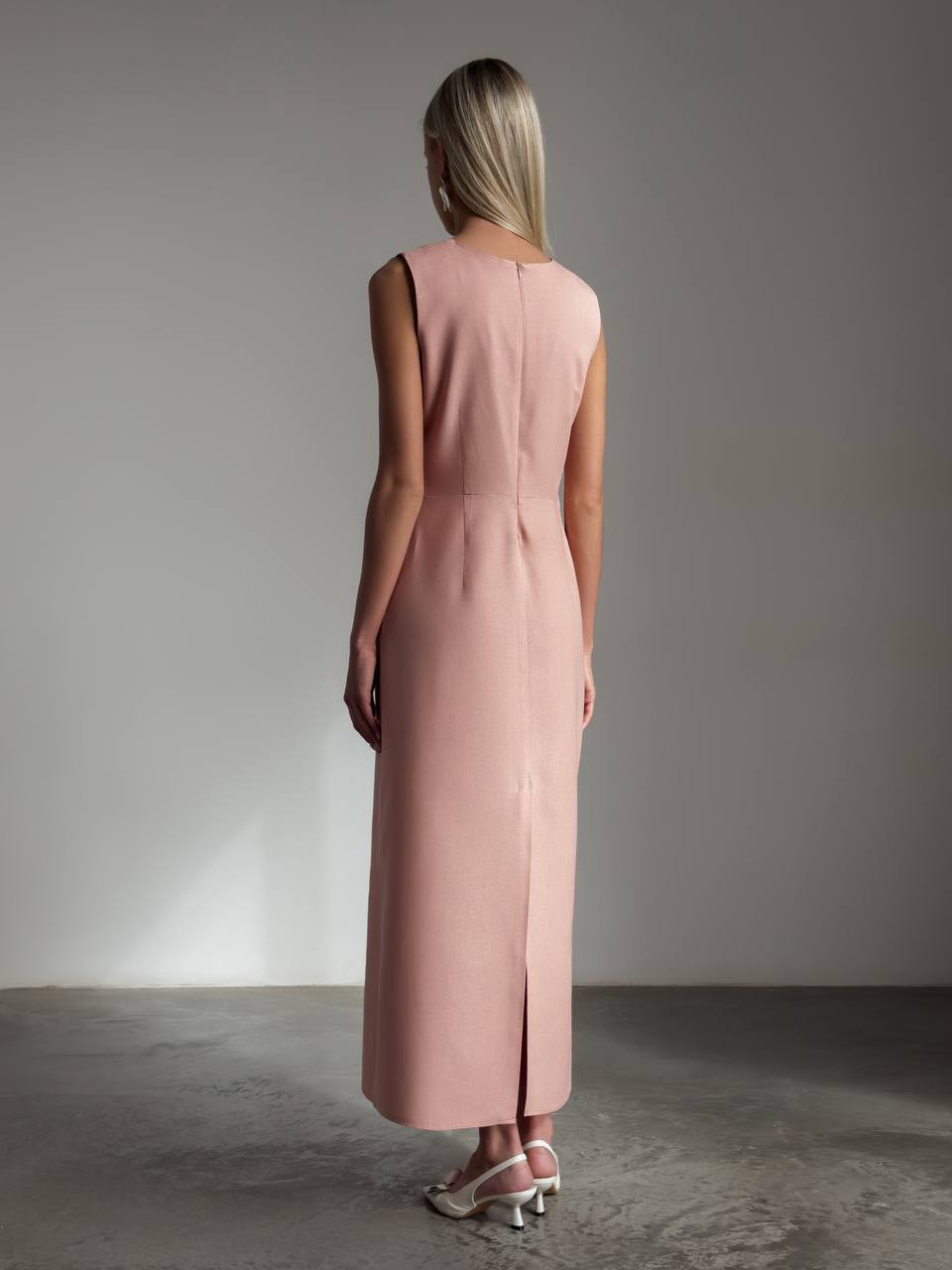 Woman wearing a pink dress standing against a plain background