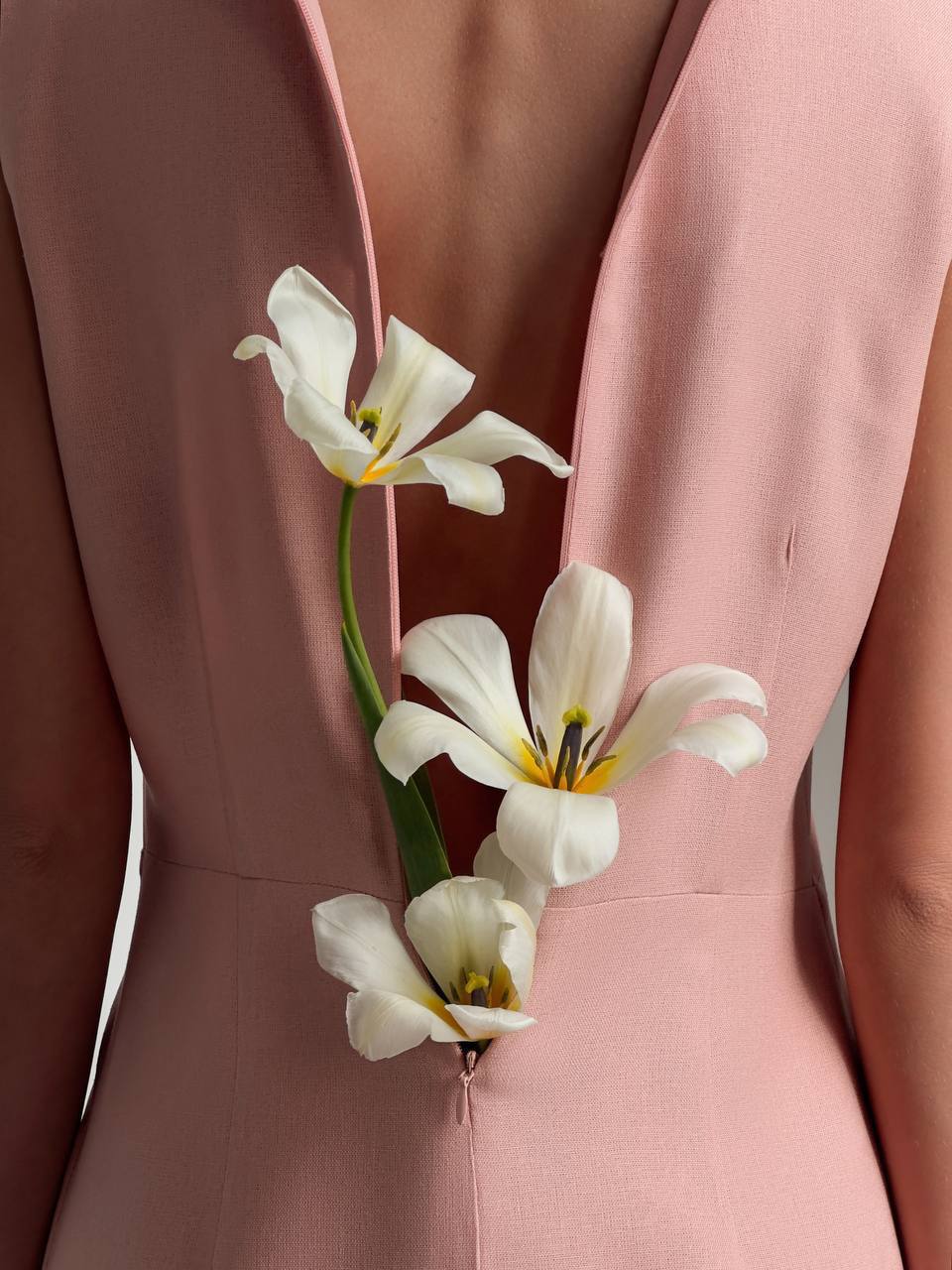White flowers with green stems attached to a pink garment.