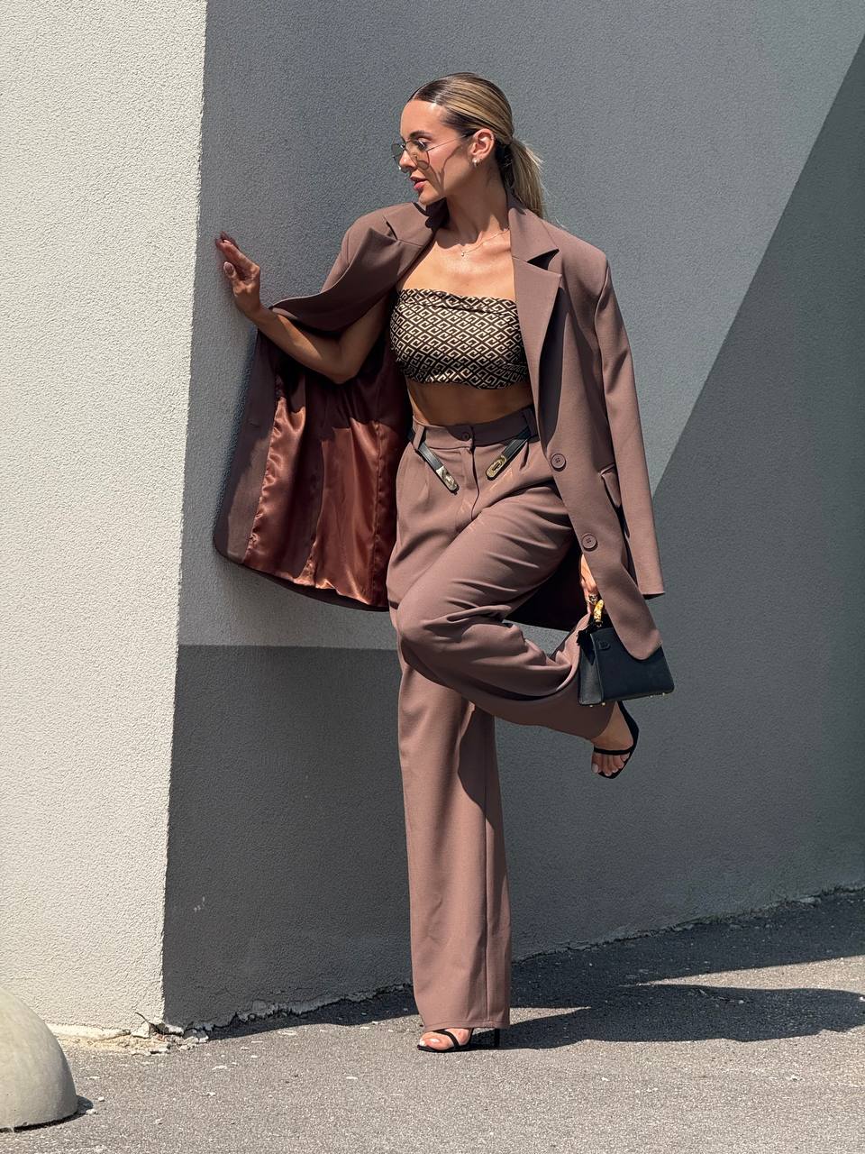 Woman in a stylish outfit standing against a gray wall