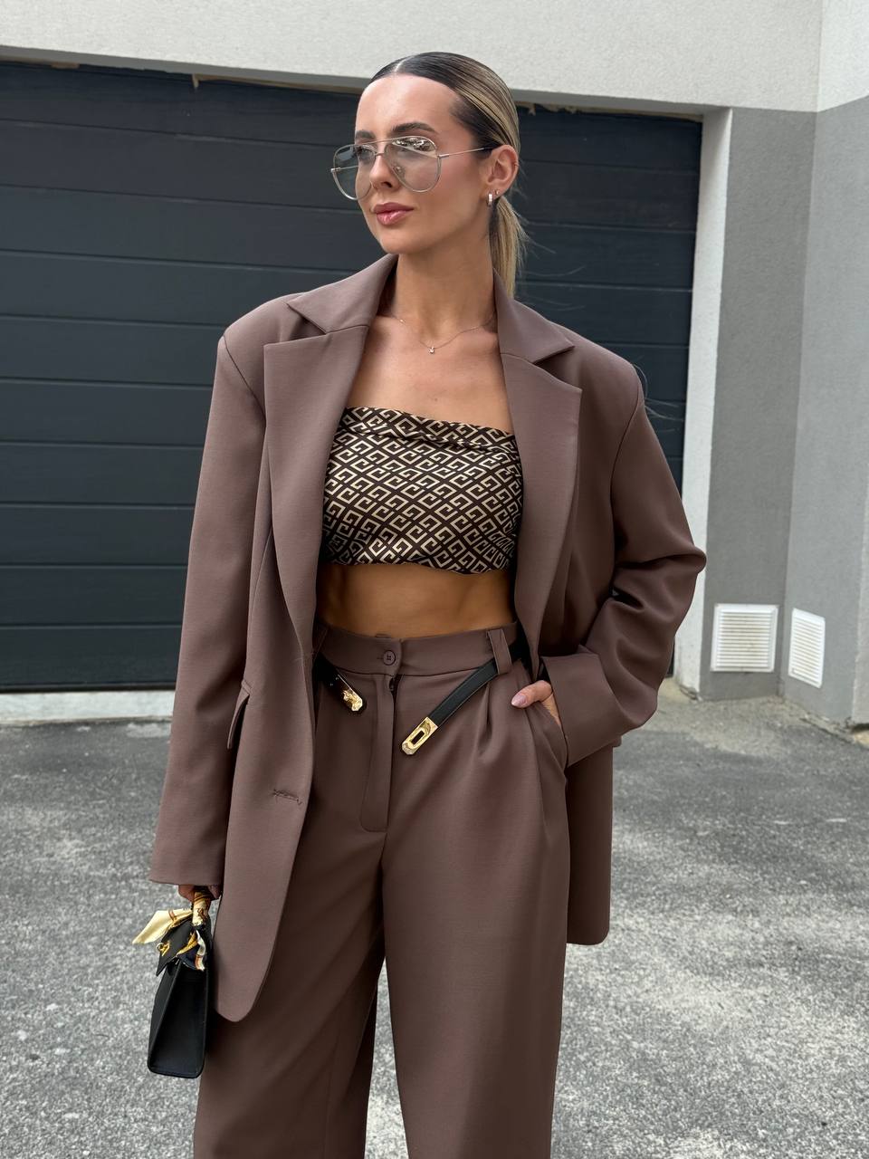 Woman in a brown outfit standing in front of a garage door.