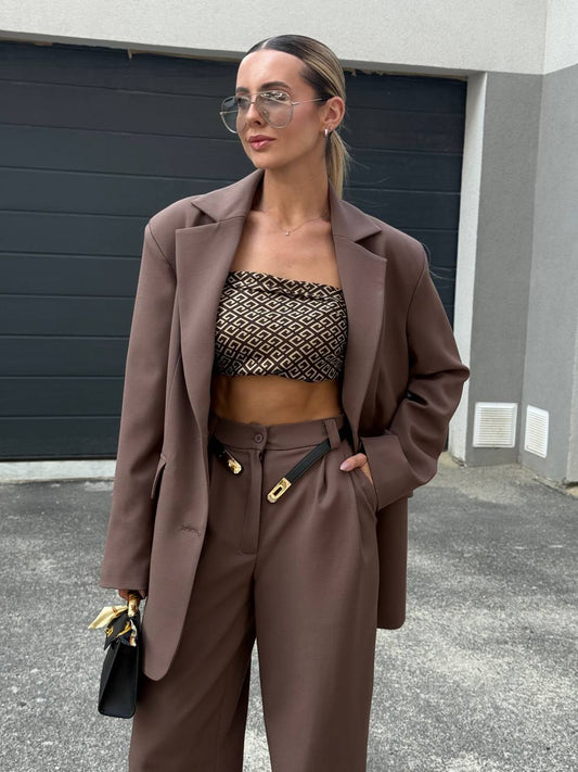 Woman in a brown outfit standing in front of a garage door.