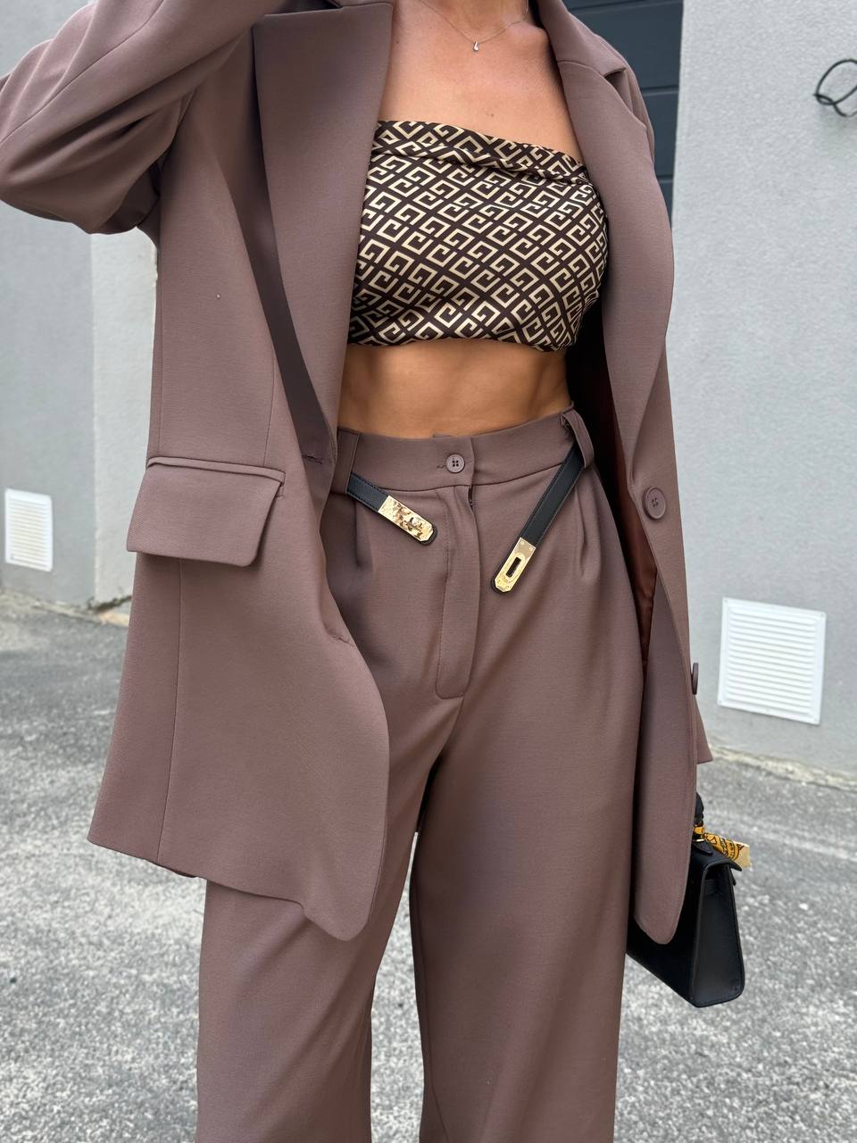 Person wearing a brown suit with a patterned top outdoors.
