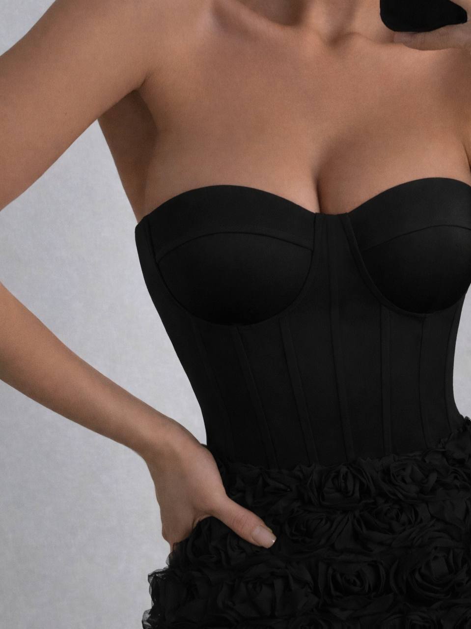 Black strapless dress with floral details on a plain background