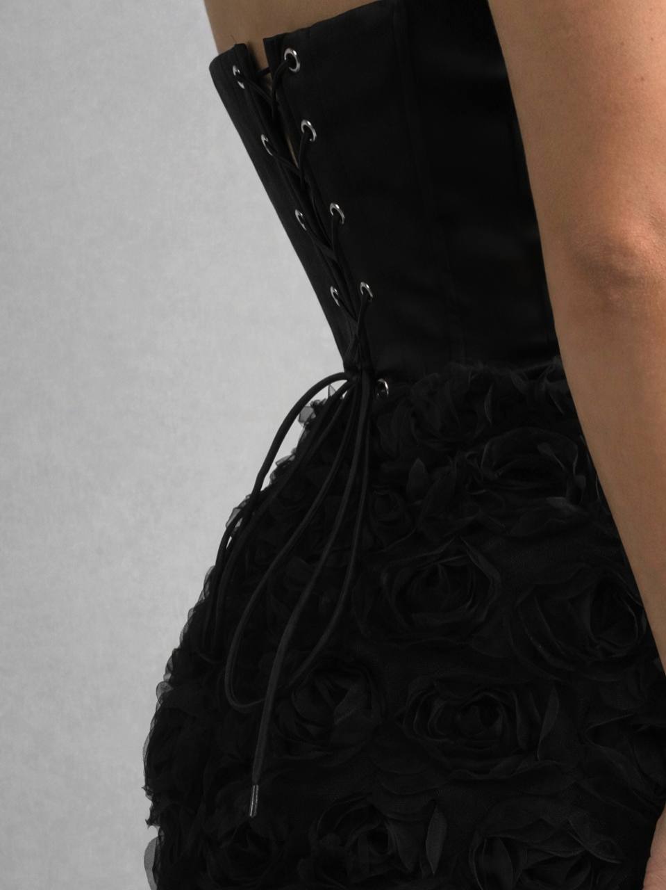 Black corset with floral details on a gray background