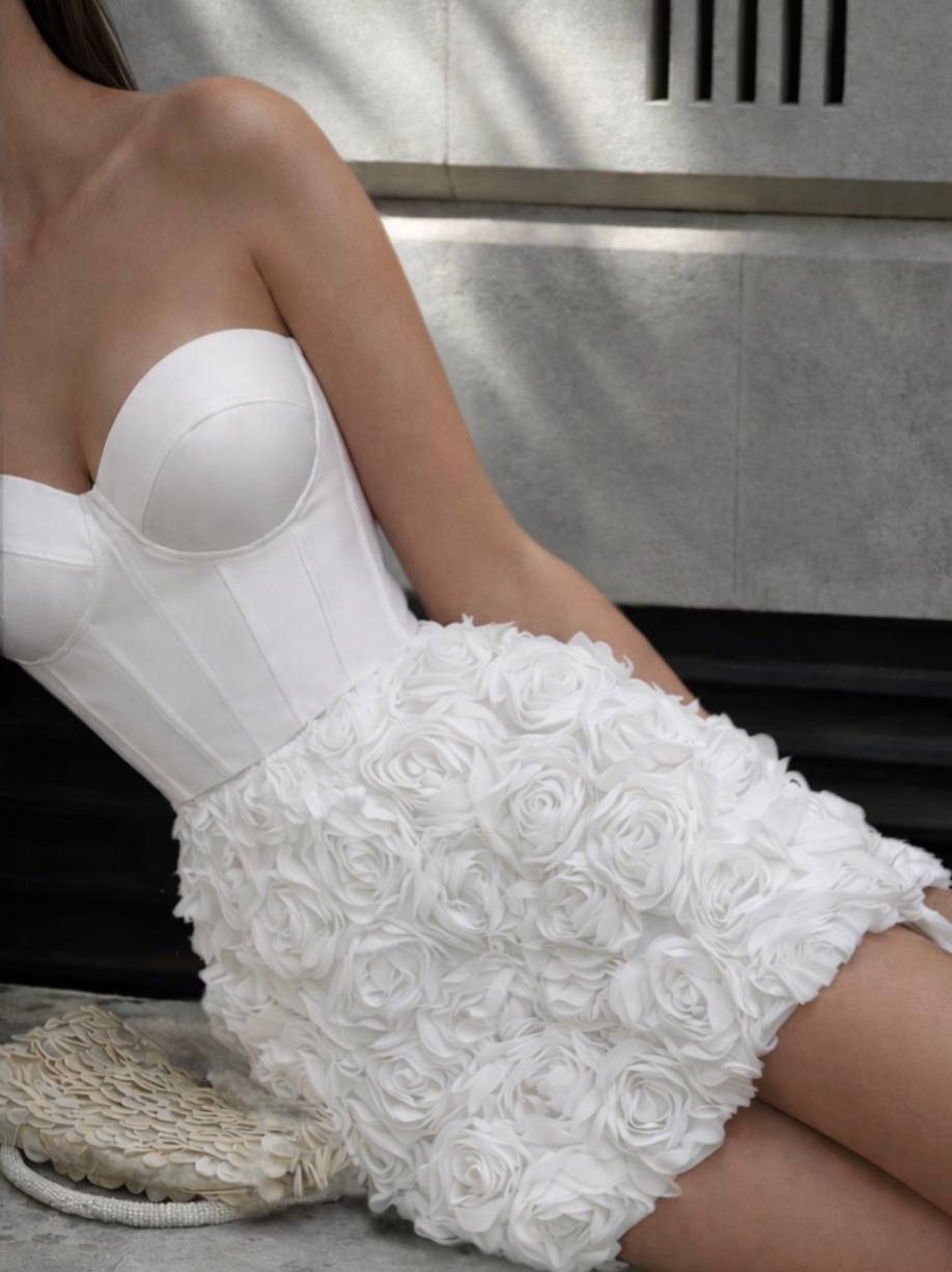 Person wearing a white strapless top and white shorts with floral details on a metallic surface.