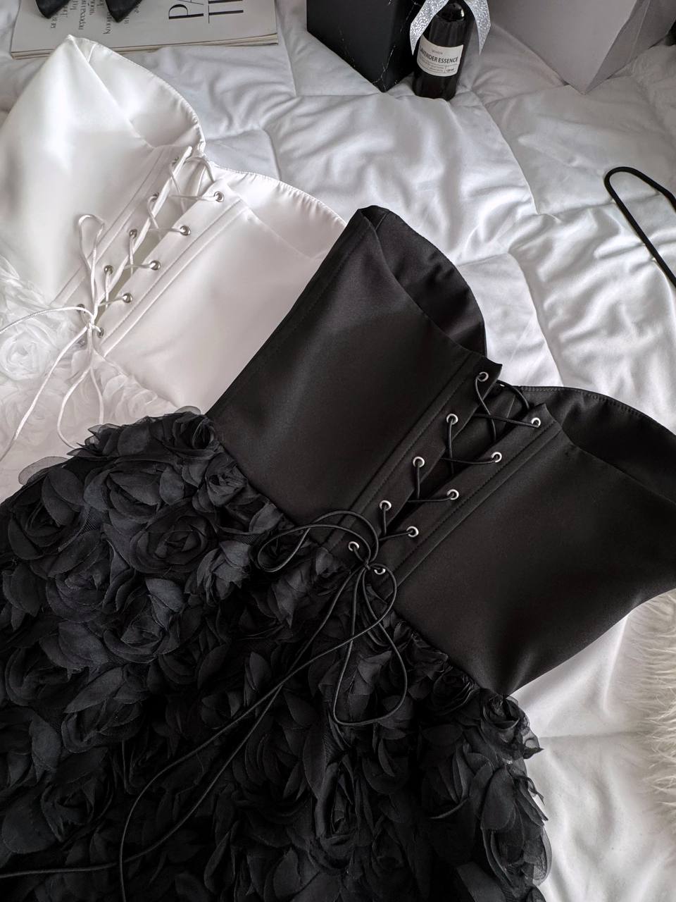 Black lace-up dress with ruffled skirt on a white bed
