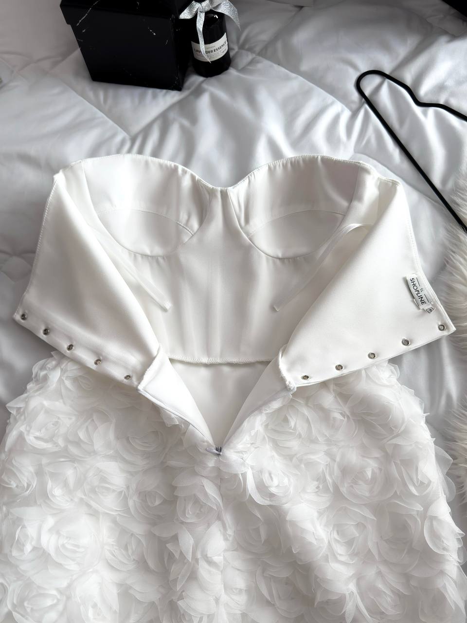 White strapless top with feathered skirt on a white surface