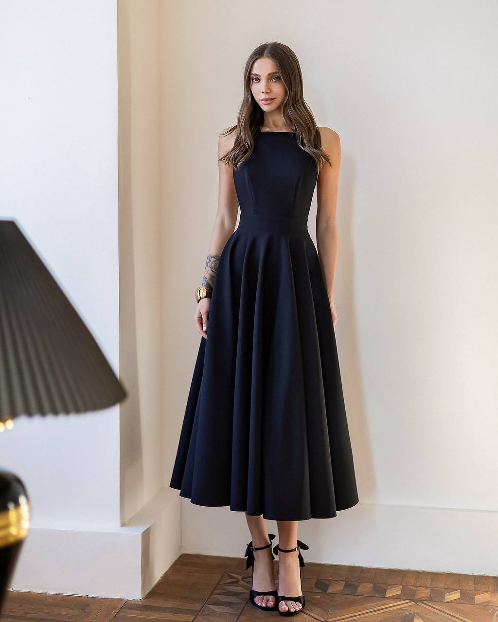 Woman wearing a black dress standing in an elegant interior setting.