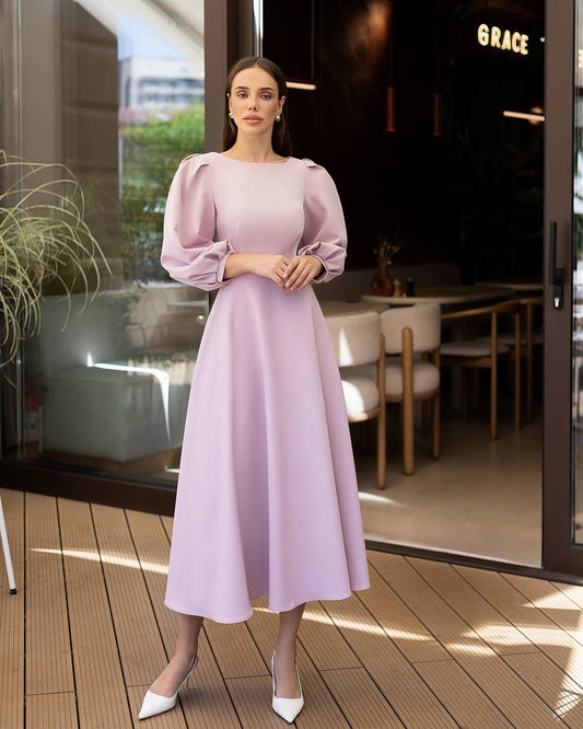 Woman in a light purple dress standing on a wooden deck with a restaurant interior in the background.