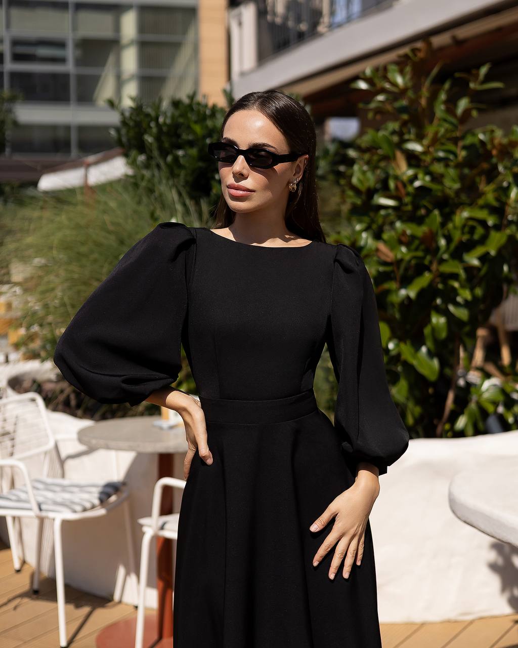 Woman wearing a black dress with puffed sleeves in an outdoor setting