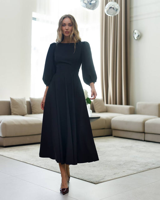 Woman in a black dress standing in a modern living room.