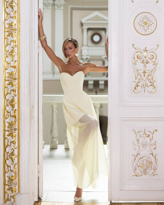 Woman in a white dress standing in an ornately decorated room.