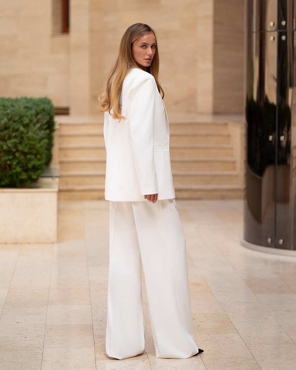 Woman in a white outfit standing outdoors with a building in the background
