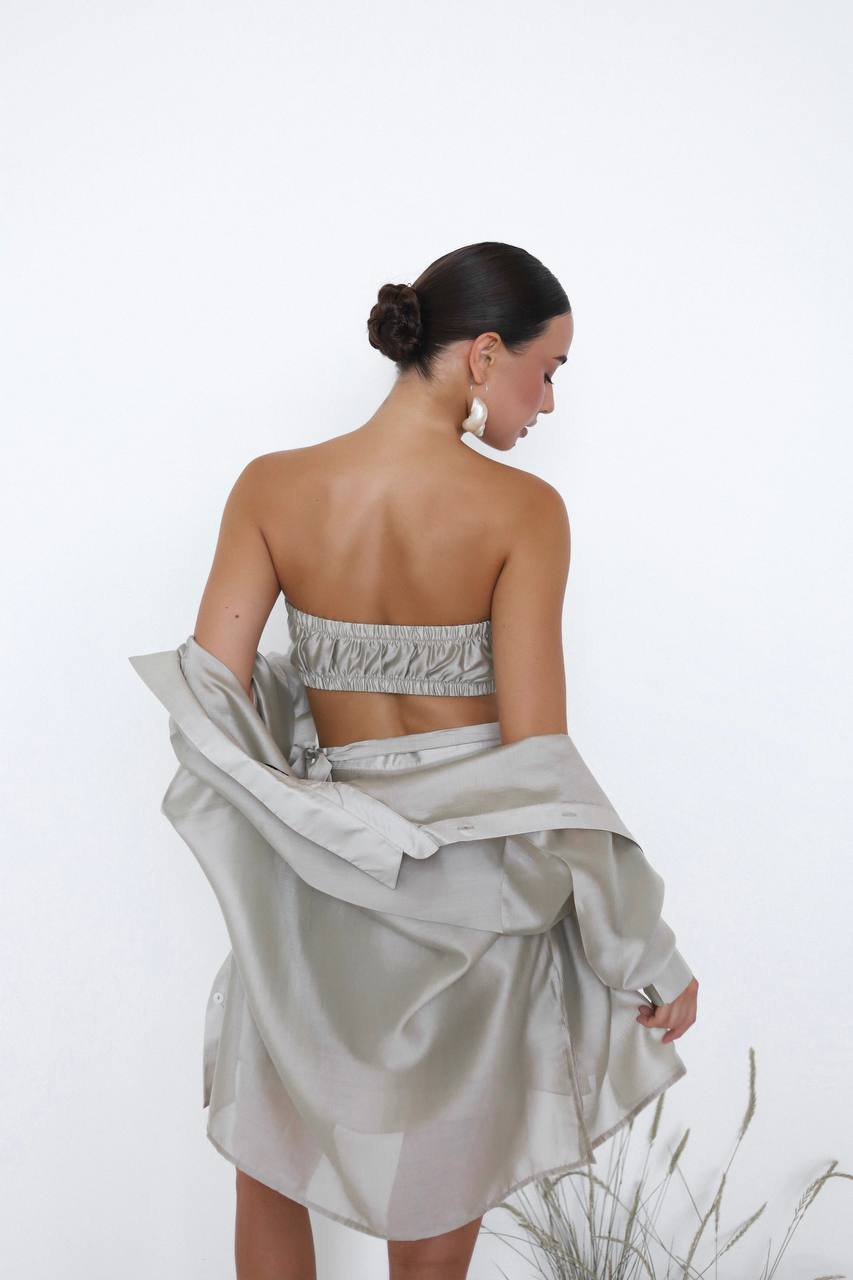 Woman wearing a strapless top and flowing skirt against a white background