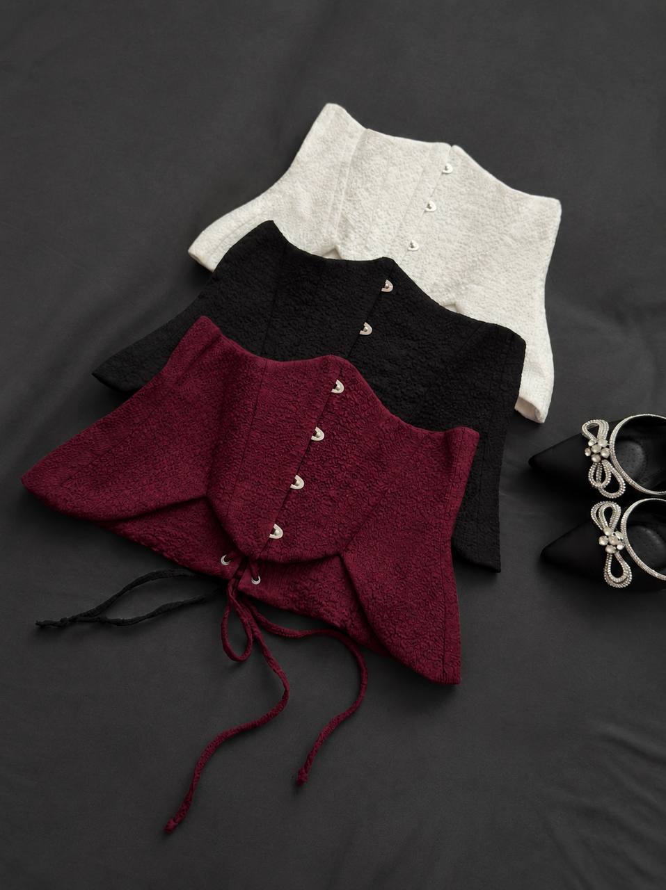 Three different colored cloaks on a dark surface