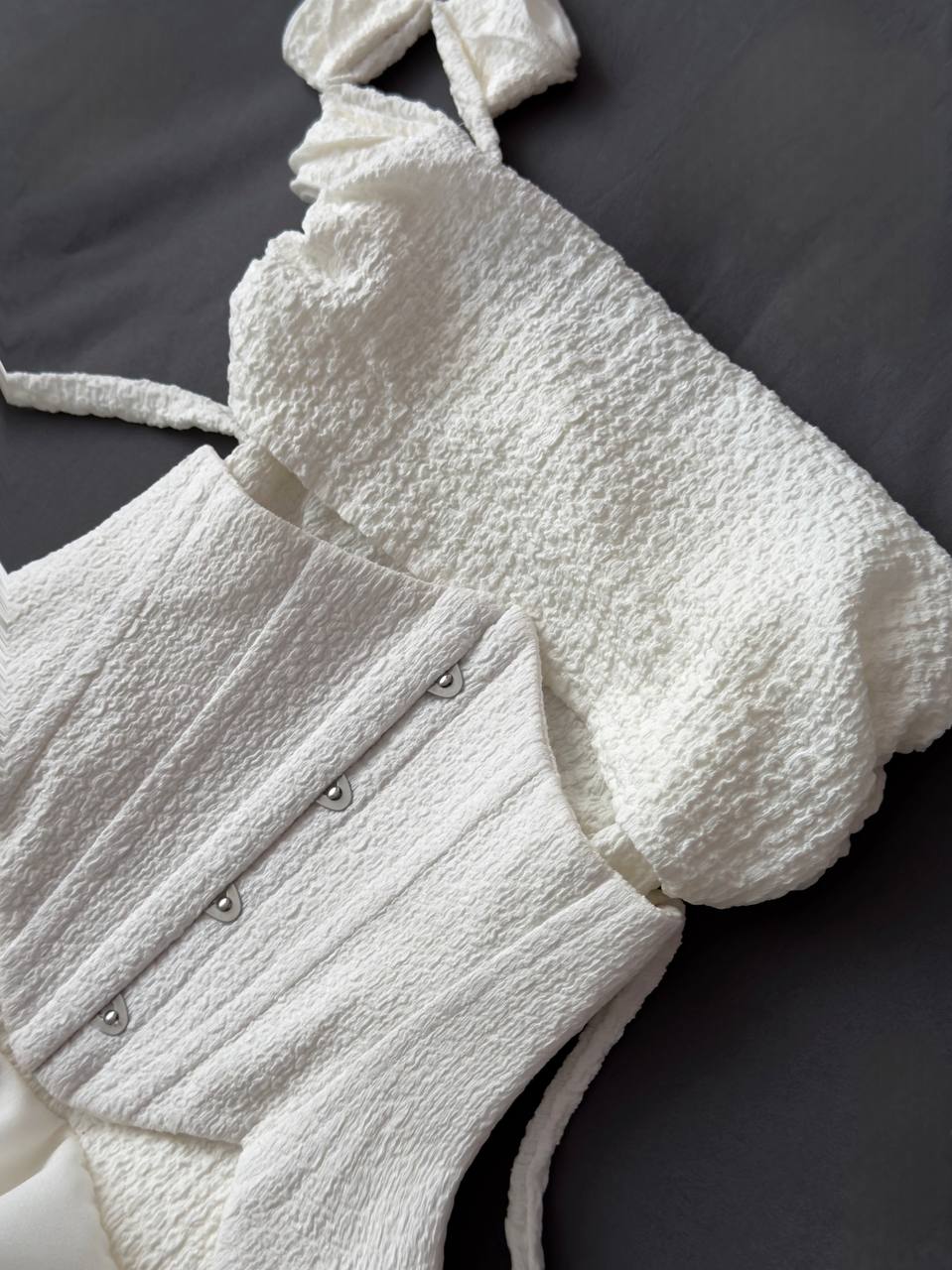 White textured garment with button details on a dark background