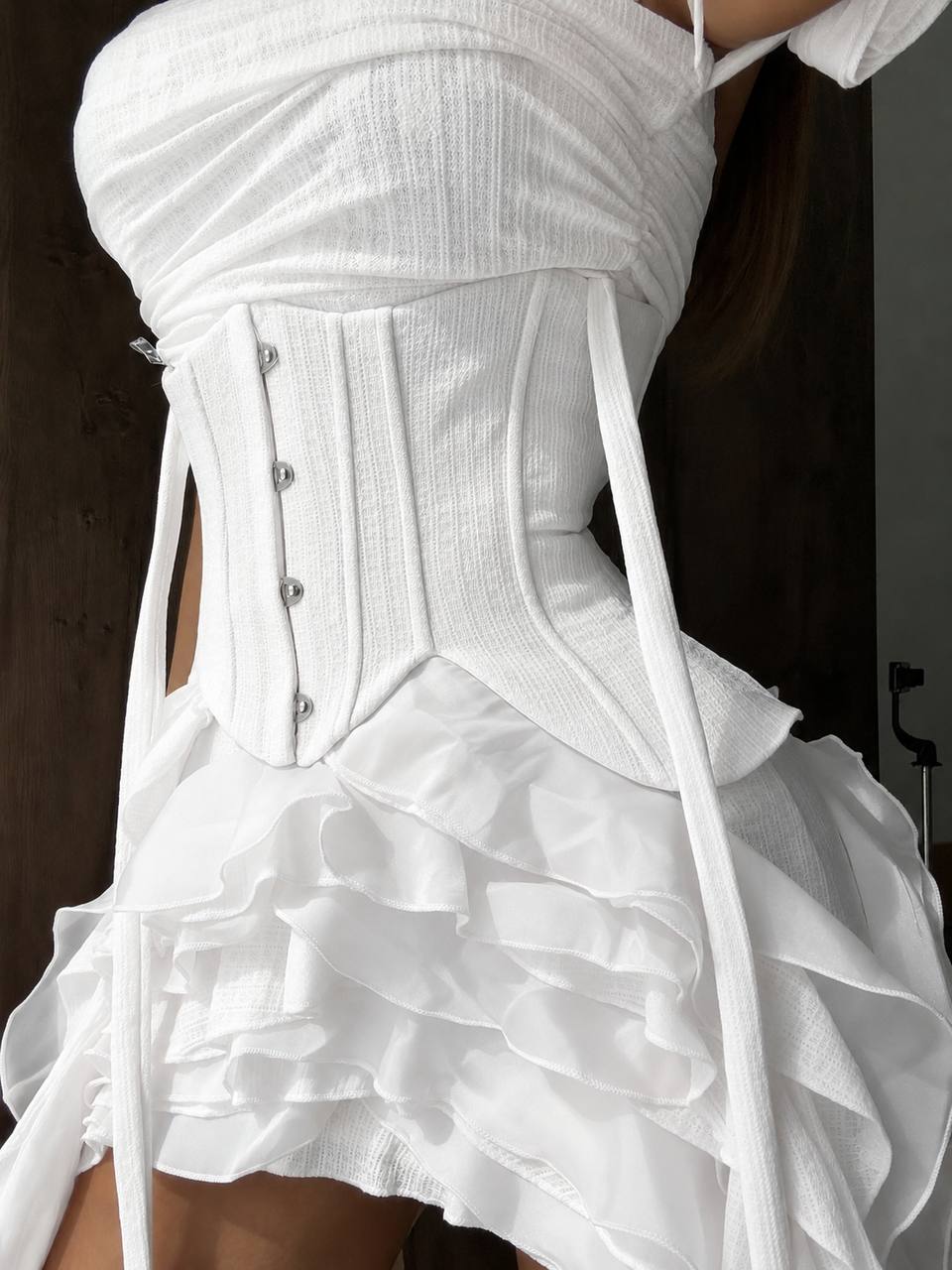 White corset dress with ruffled skirt on a dark background