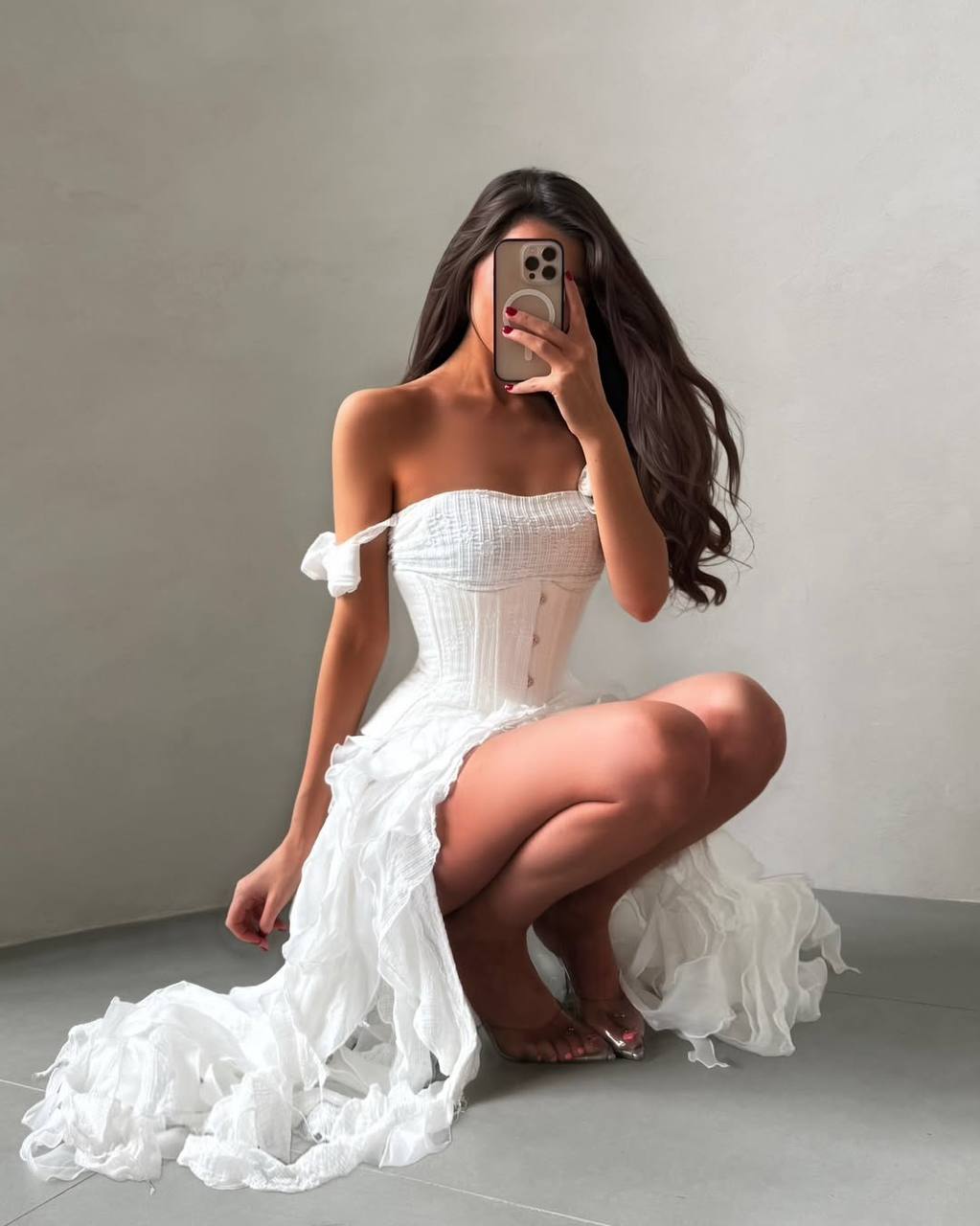 Woman in a white off-shoulder dress posing against a plain background