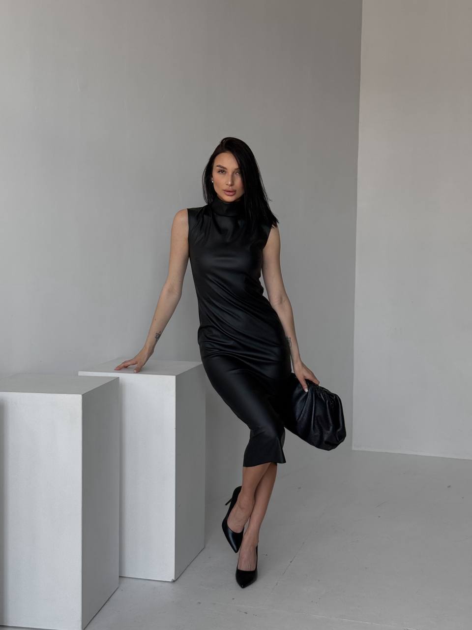 Woman in a black dress posing against a plain background