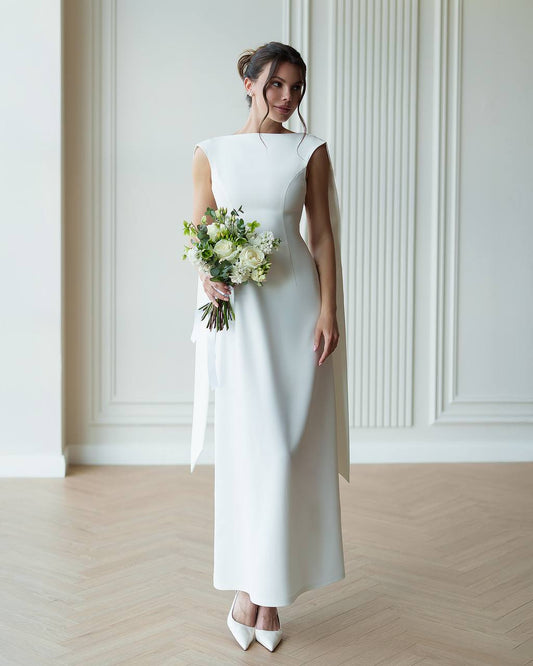 Woman in a white wedding dress holding a bouquet in a minimalistic setting