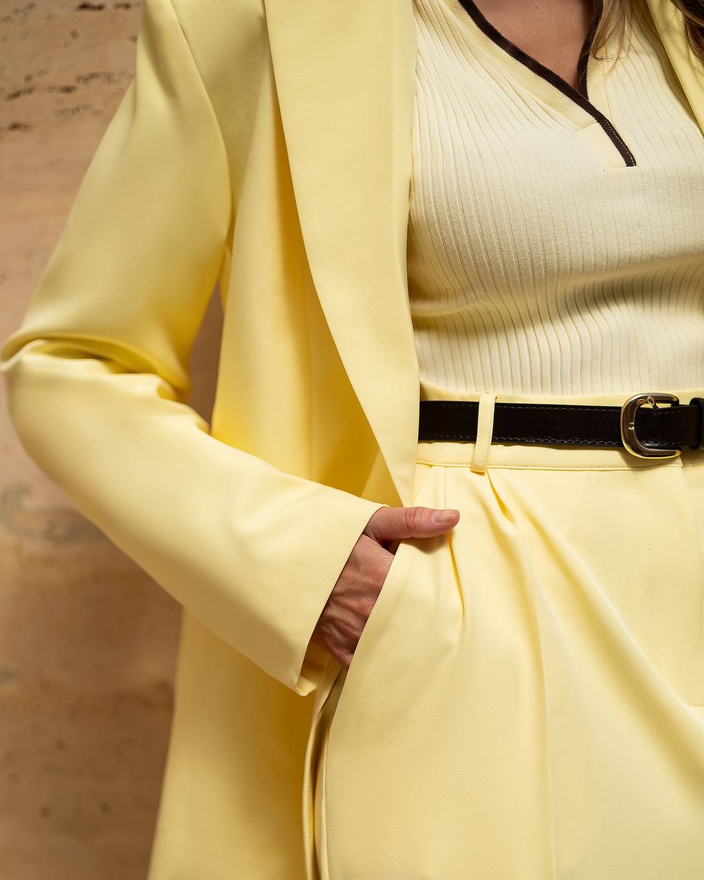 Yellow suit with a black belt on a neutral background