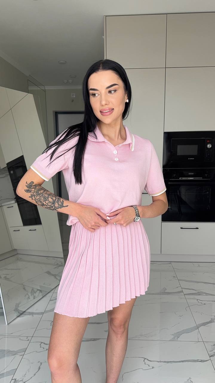 Woman in a pink dress standing in a modern kitchen.