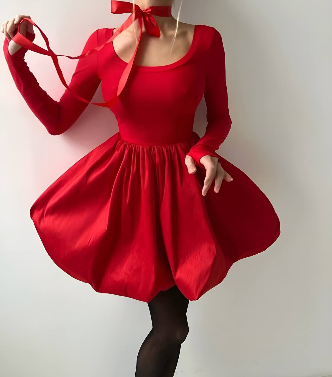 Red dress with long sleeves and a bow detail on a plain background