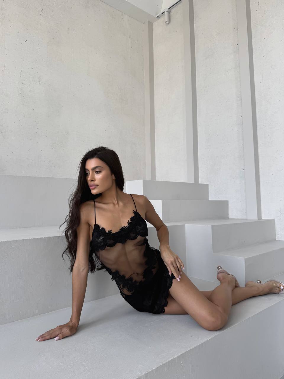 Woman in black lace lingerie sitting on a staircase.