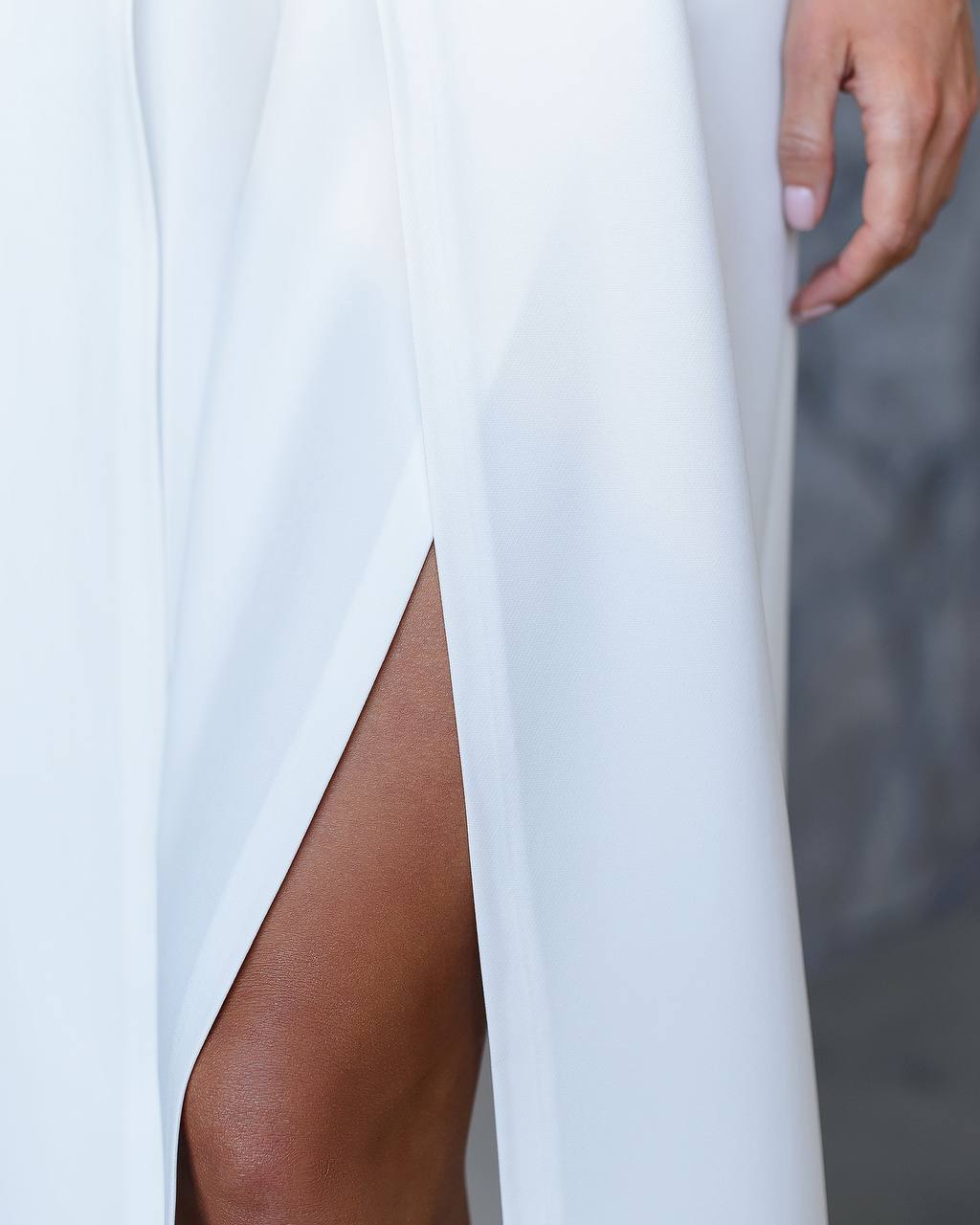 White dress with a slit, showing a person's leg and hand.