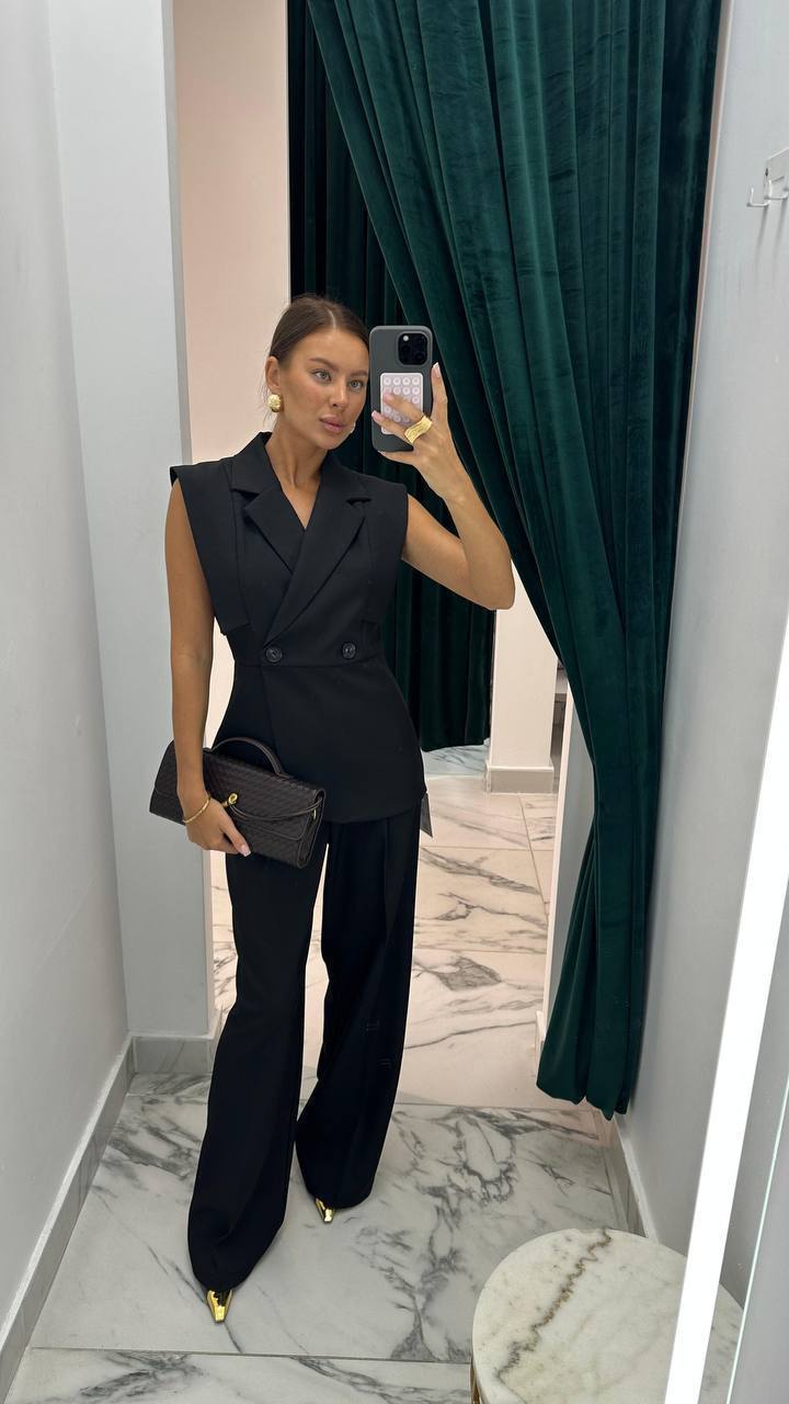 Person taking a mirror selfie wearing a black outfit in a room with green curtains.