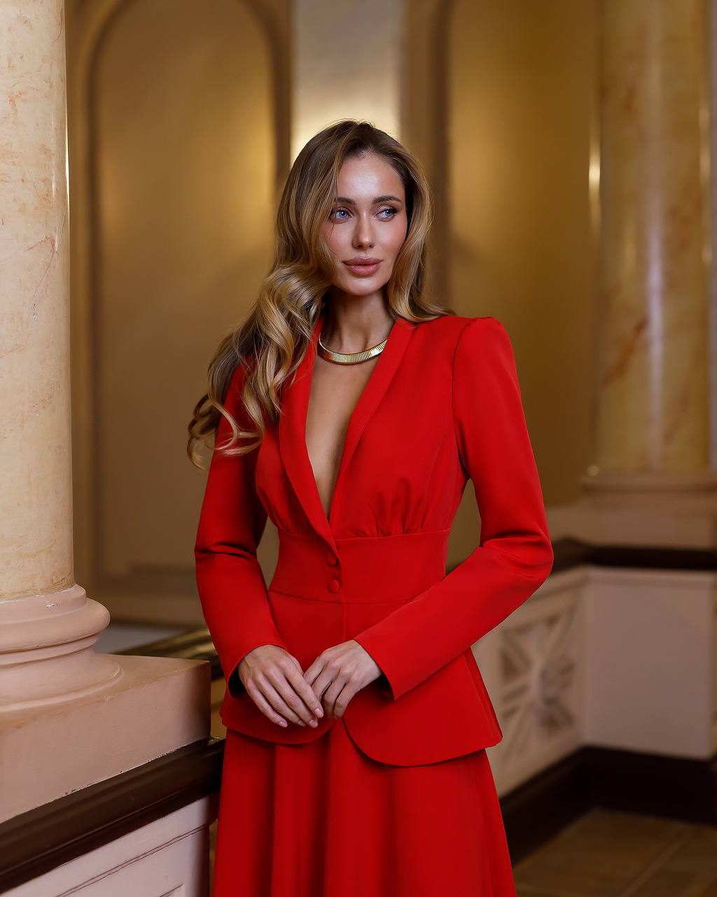 Woman in a red outfit standing in an elegant interior setting