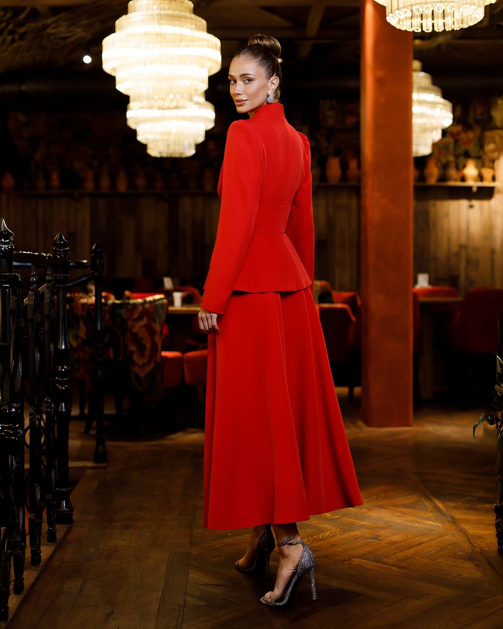 Woman in a red outfit standing in a dimly lit restaurant.