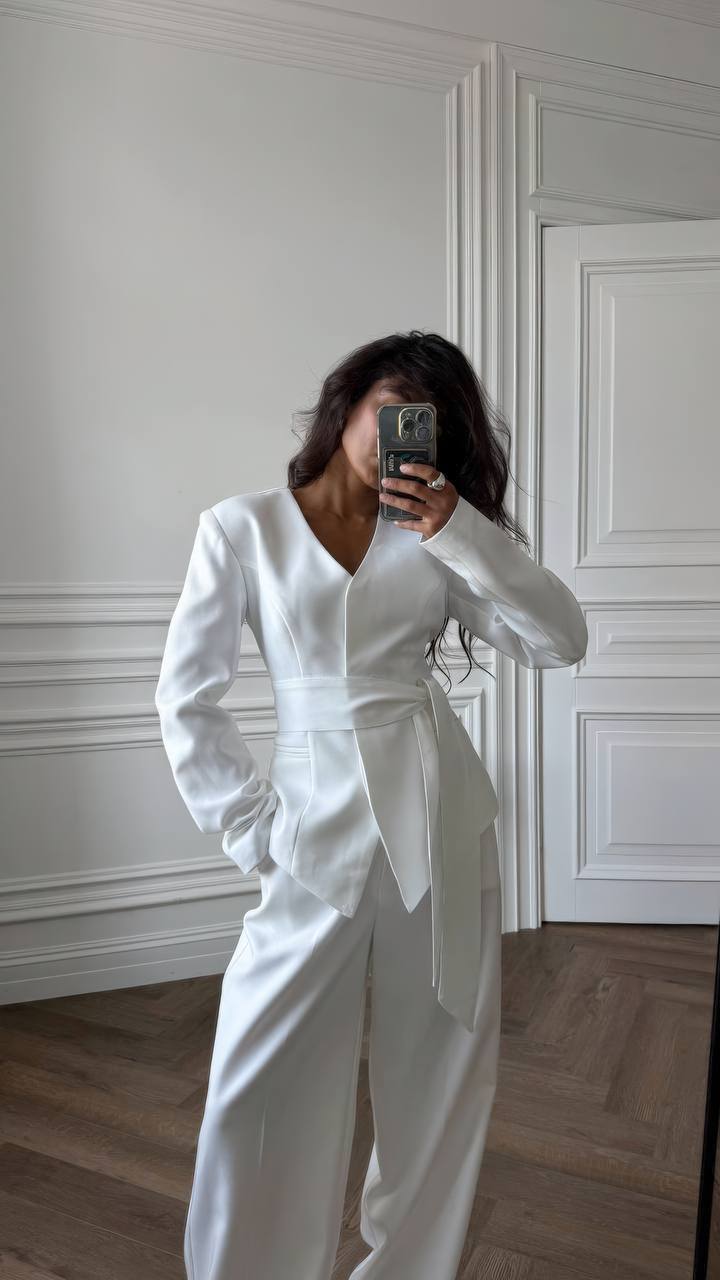 Person wearing a white outfit in a room with white walls and wooden floor.
