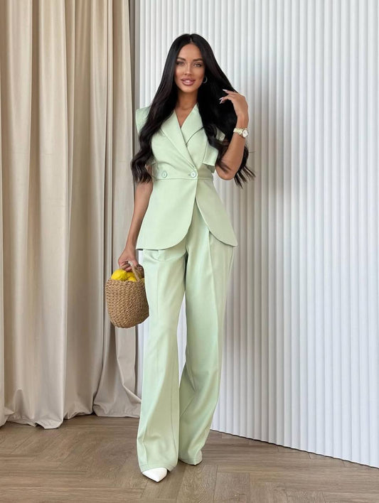 Woman in a light green suit holding a woven basket against a neutral background