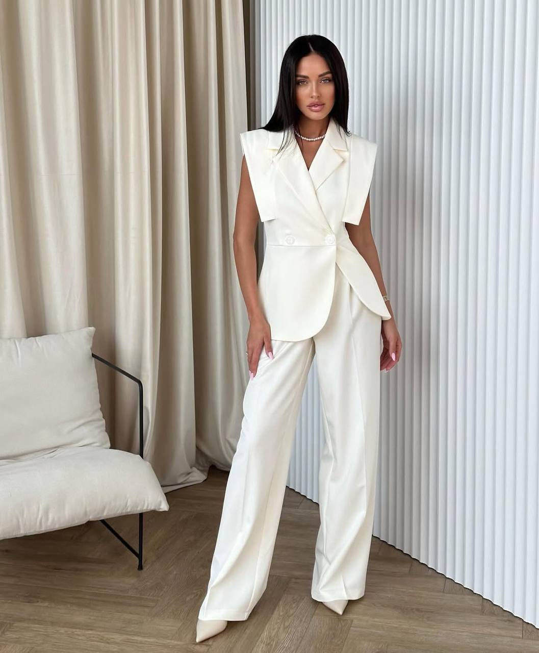 Woman in a white outfit standing in a room with neutral decor